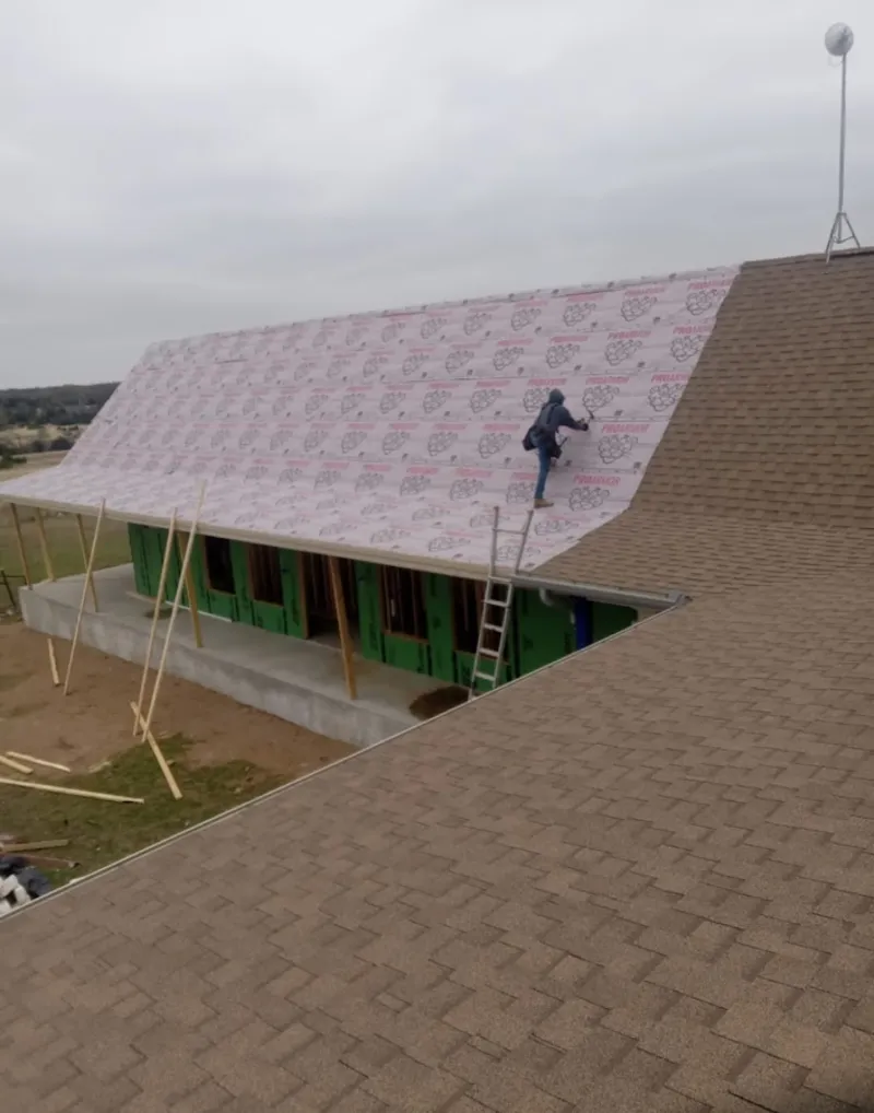 Worker preparing underlayment for a metal roof installation in Spring Lake